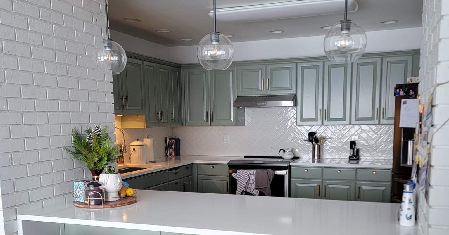 A spotless modern kitchen with sage green cabinets — cleaned by Ari's team